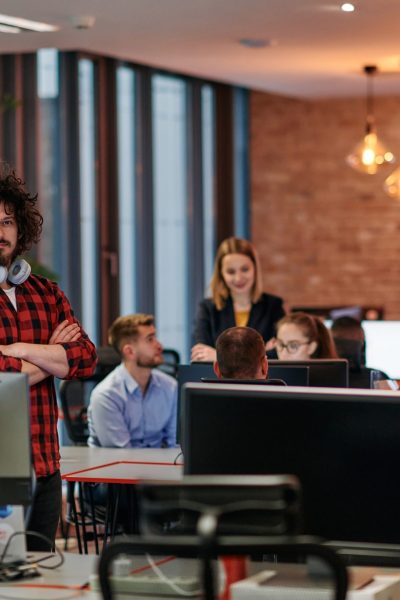 In a contemporary office setting, a diverse group of business professionals engage in a focused discussion while utilizing computers to strategize and plan business initiatives.